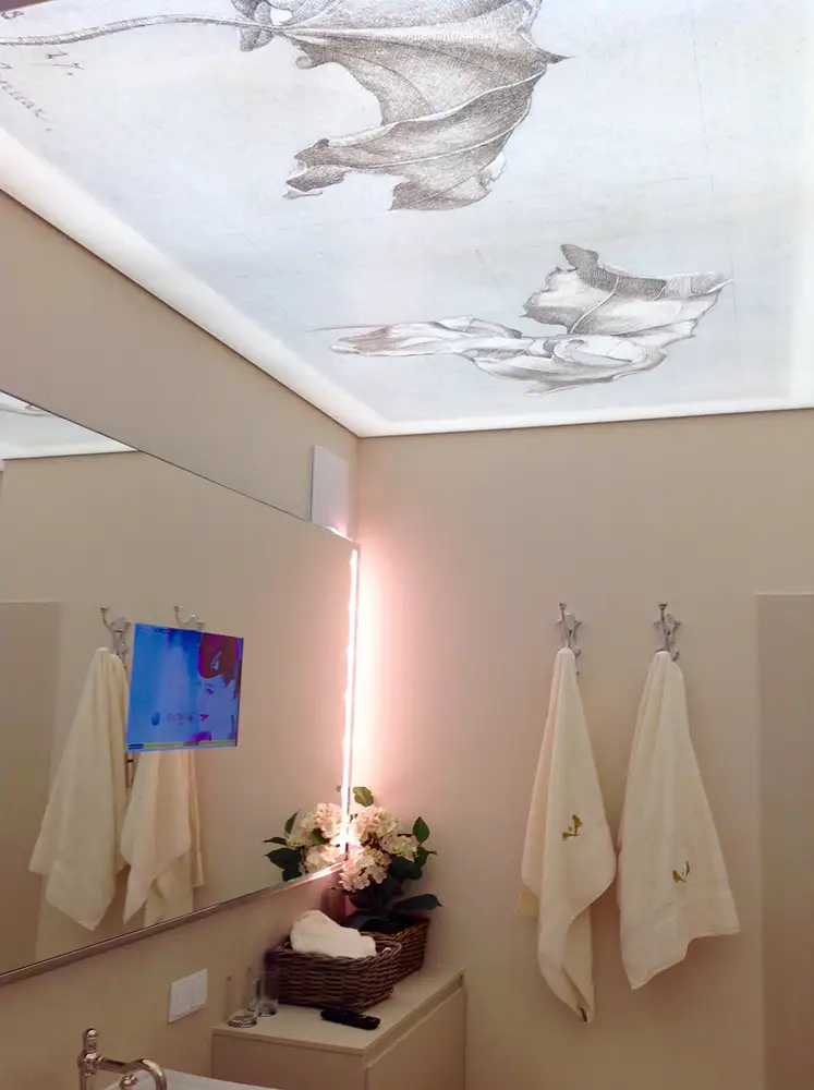 Die Decke im Bad zeigt eine hinterleuchtete Lichtdecke mit dezenten Blättern bedruckt